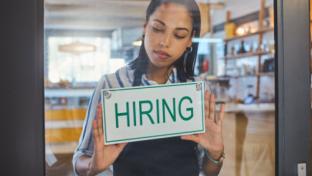 Woman putting up a hiring sign