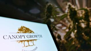 Smartphone with logo of Canadian cannabis company Canopy Growth Corporation on screen in front of web page. Focus on centre-right of phone display.