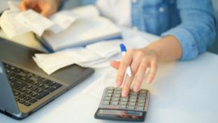 oman using a pen writing on bank account book while holding the bills to calculate. Expenses, account, taxes, home budget concept