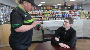 A 7-Eleven staffer takes the order from a customer seated in the restaurant