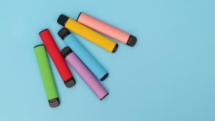 Multiple colourful vapes on a blue background.