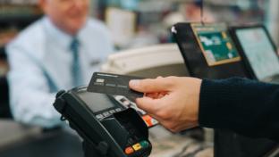 Close-up of a unrecognisable person using credit card to pay at grocery store. Customer making a payment for the purchase using his nfc card at supermarket.